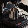 Espresso kannetje onder een machine en op een koffie weegschaal