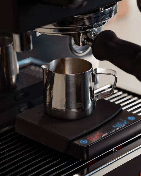 Espresso kannetje onder een machine en op een koffie weegschaal