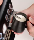 Barista creating milk foam for latte art in Stainless Steel Milk pitcher latte art Essentials 600ml black