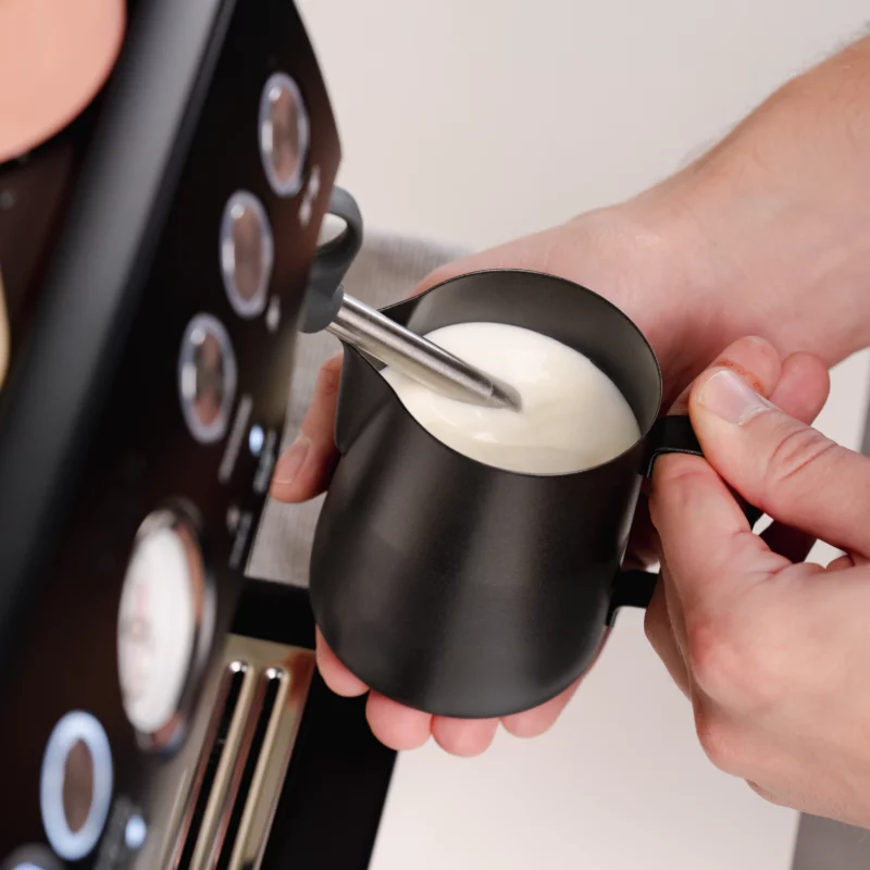 Barista creating milk foam for latte art in Stainless Steel Milk pitcher latte art Essentials 600ml black