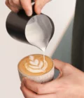 Barista creating latte wart with foam from a  Stainless Steel Milk pitcher latte art Essentials 600ml black