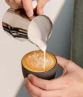 Barista creating latte art with foam from a Stainless Steel Milk pitcher latte art Essentials 350ml Italian style