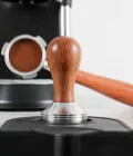 tamper 51mm made of wood on a tamping mat with naked portafilter and delonghi dedica on the background