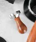 tamper 51mm made of wood on a tamping mat with naked portafilter and delonghi dedica on the background