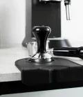 tamper 51mm on a tamping mat with naked portafilter and delonghi dedica on the background